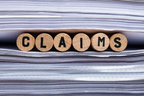 Wooden Cork With Claims Text Between The Stacked Files