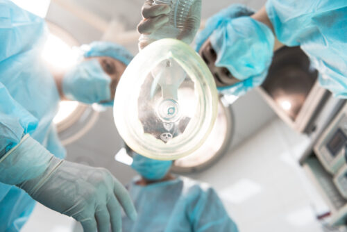 Close up of the anesthetic mask and three doctors being together