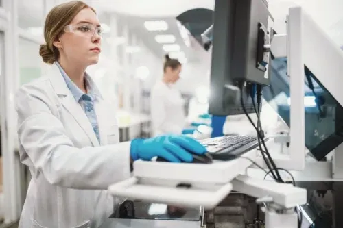 A team of laboratory technicians conduct a series of tests on a chemical analyzer in a biological laboratory. Two female scientists work in a modern equipped computer laboratory