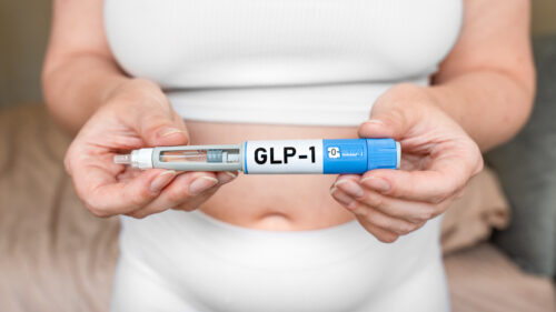 GLP-1 injection pen held near the abdomen